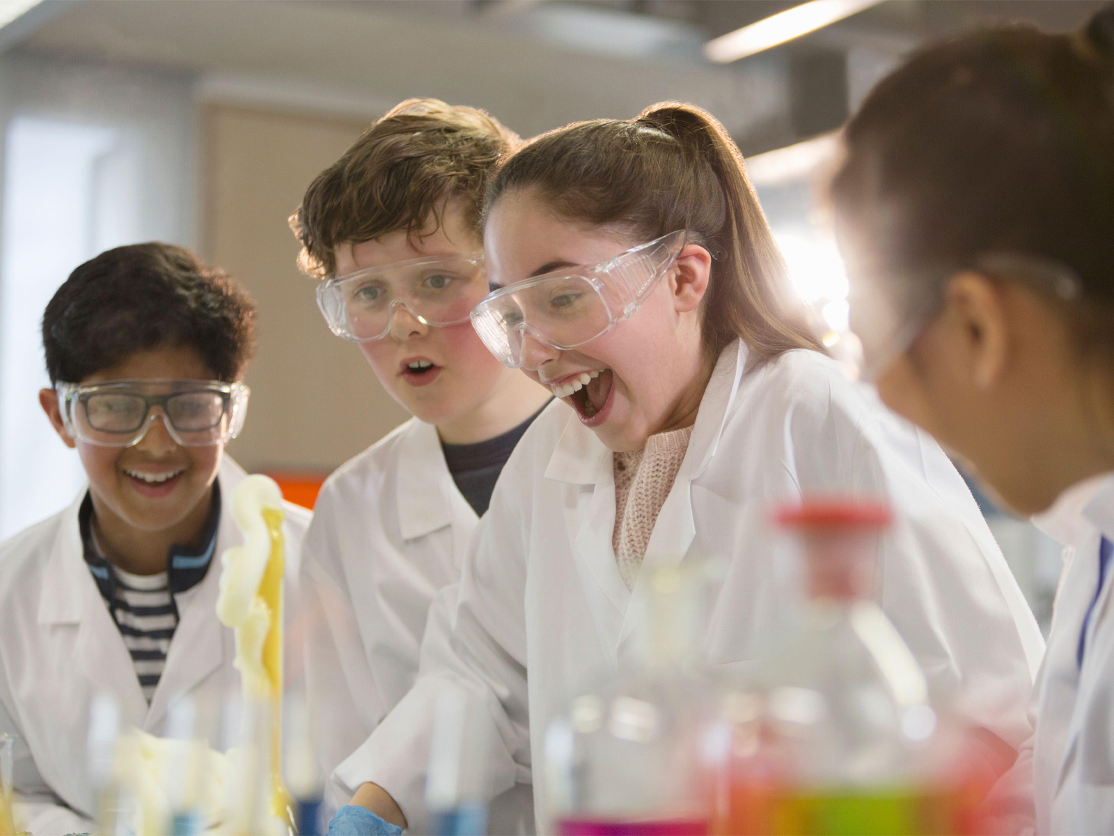 excited children with science experiment in lab coats and protective glasses