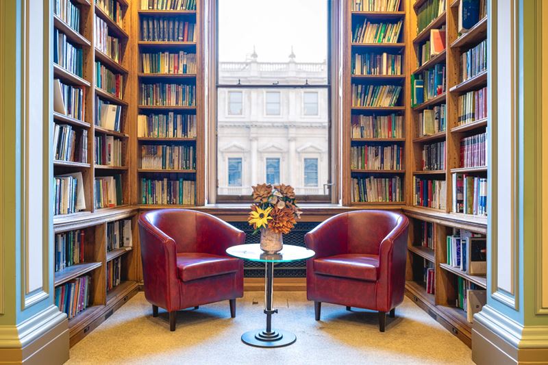 Two chairs in library against window and bookshelf backdrop